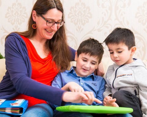 Eine Sonderpädagogin hilft zwei Kindern beim Erledigen von Hausübungen.