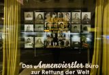 Eine Menge Porträts von Viertelbewohner:innen im Schaufenster des Büros zur Rettung der Welt.