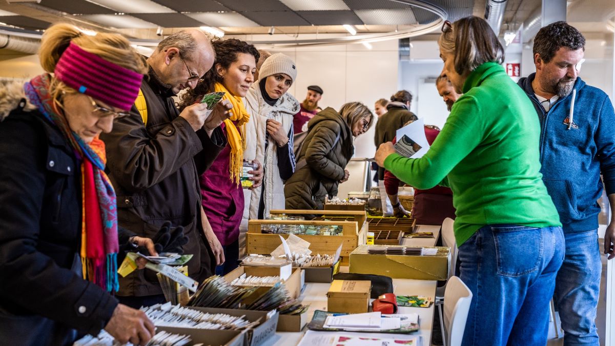 Menschen treffen sich an einem Stand, um Saatgut zu tauschen und verschenken